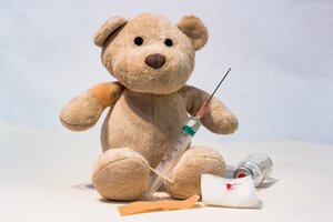 Beispielbild Kinderimpfung, Teddybär mit Pflaster und Spritze