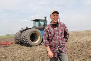 Landwirt vor einem Traktor auf einem Feld.