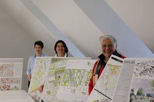 Drei Frauen mit großen Planungsskizzen eines Studienprojekts.