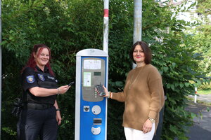 zwei Frauen neben einem Parkscheinautomaten