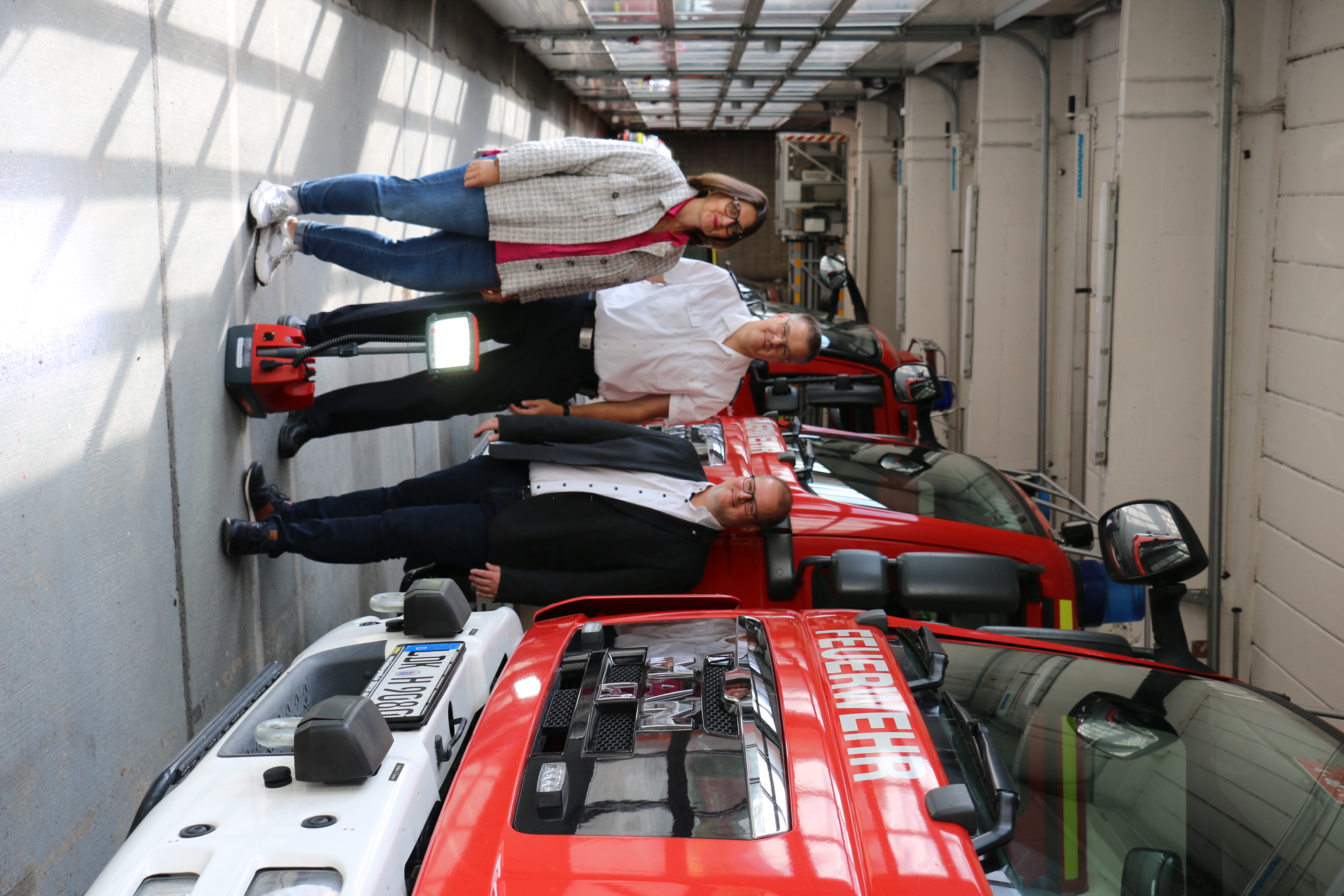 Bild von Spendenübergabe, drei Personen in der Fahrzeughalle der Feuerwehr